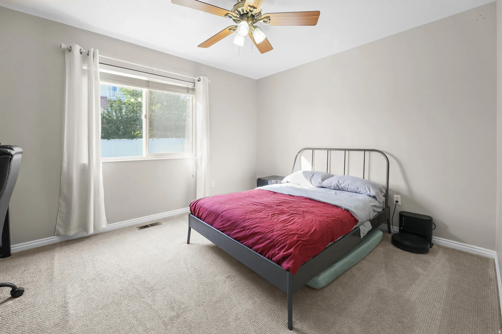 Carpeted room featuring a ceiling fan with light fixture, neutral wall paint, and a double window