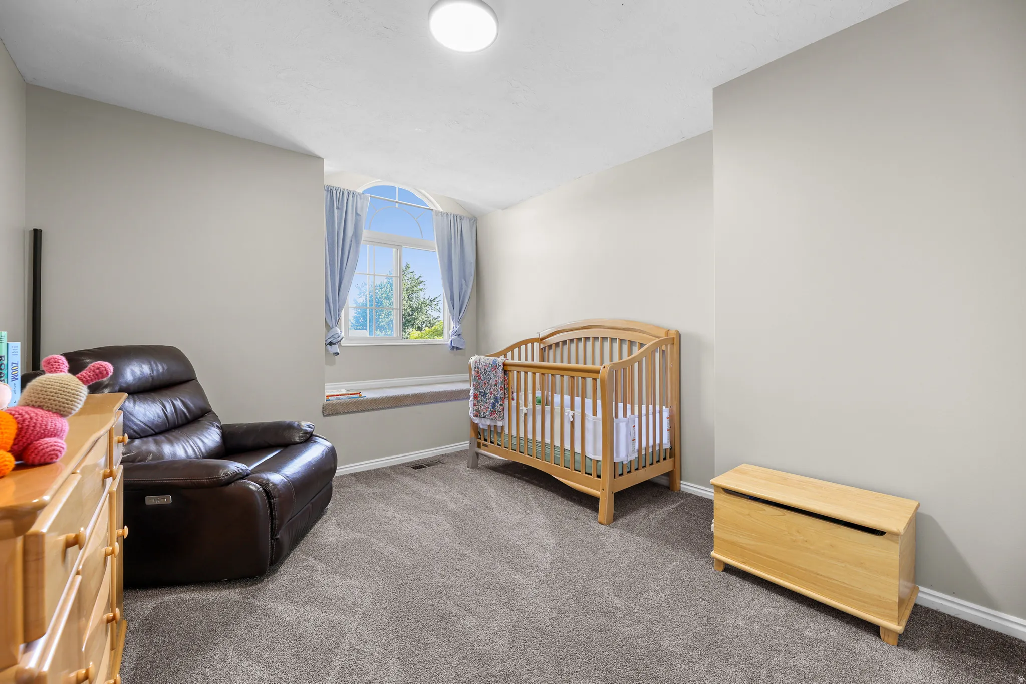 Bedroom featuring neutral wall colors, grey carpet, and a prominent arched window