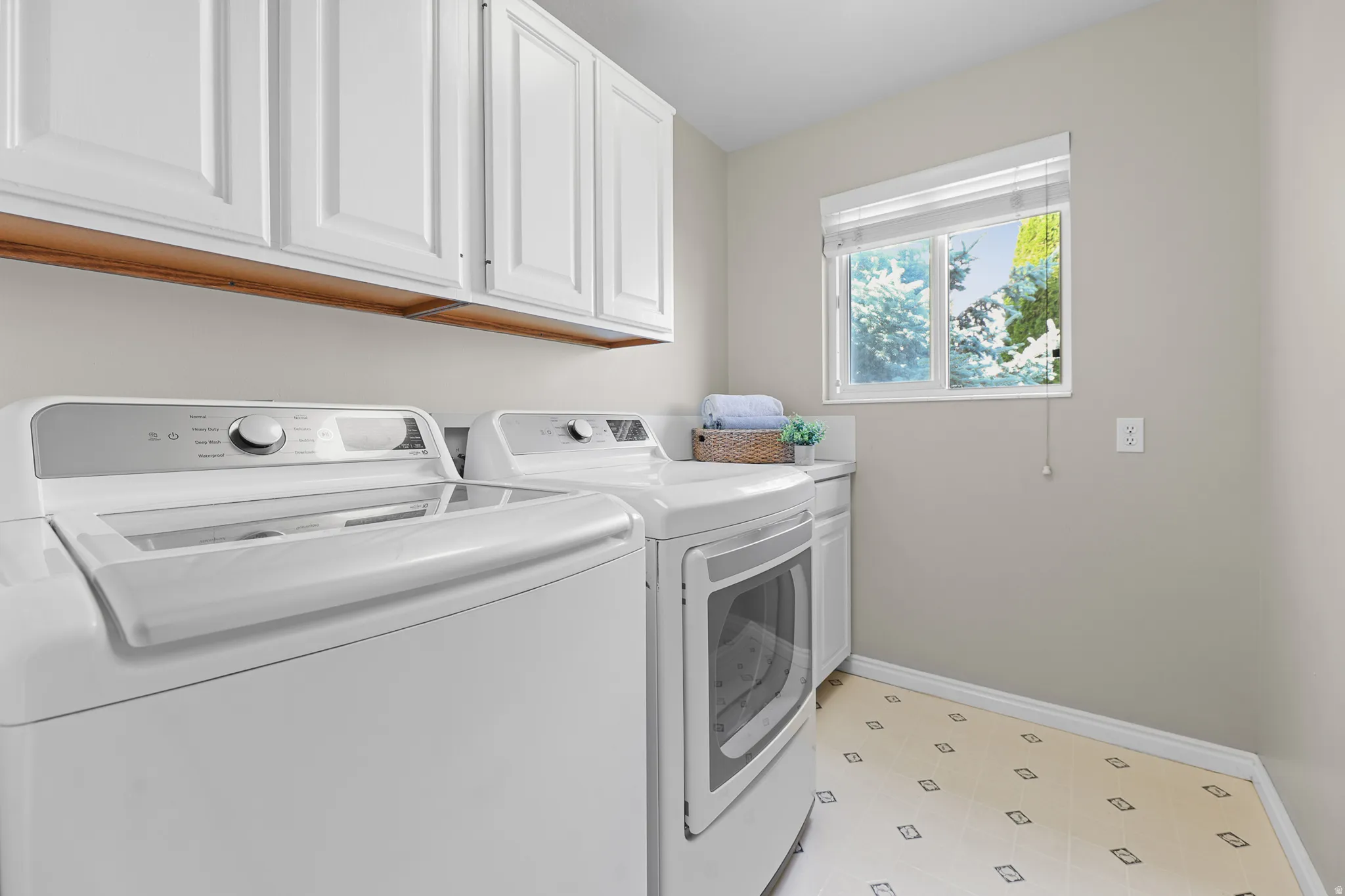 Laundry area featuring white cabinetry, a window, and patterned flooring