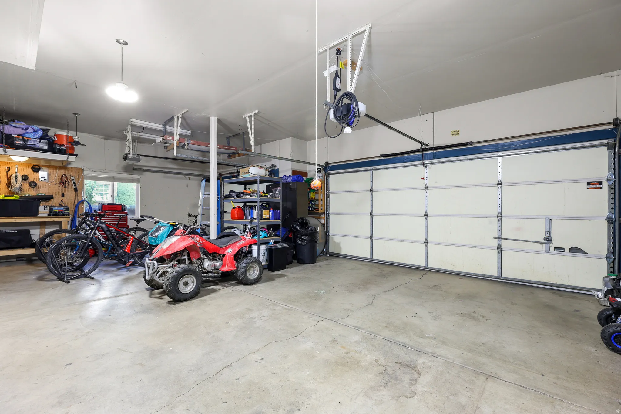 Spacious garage featuring a concrete floor, overhead lighting, and a wide garage door