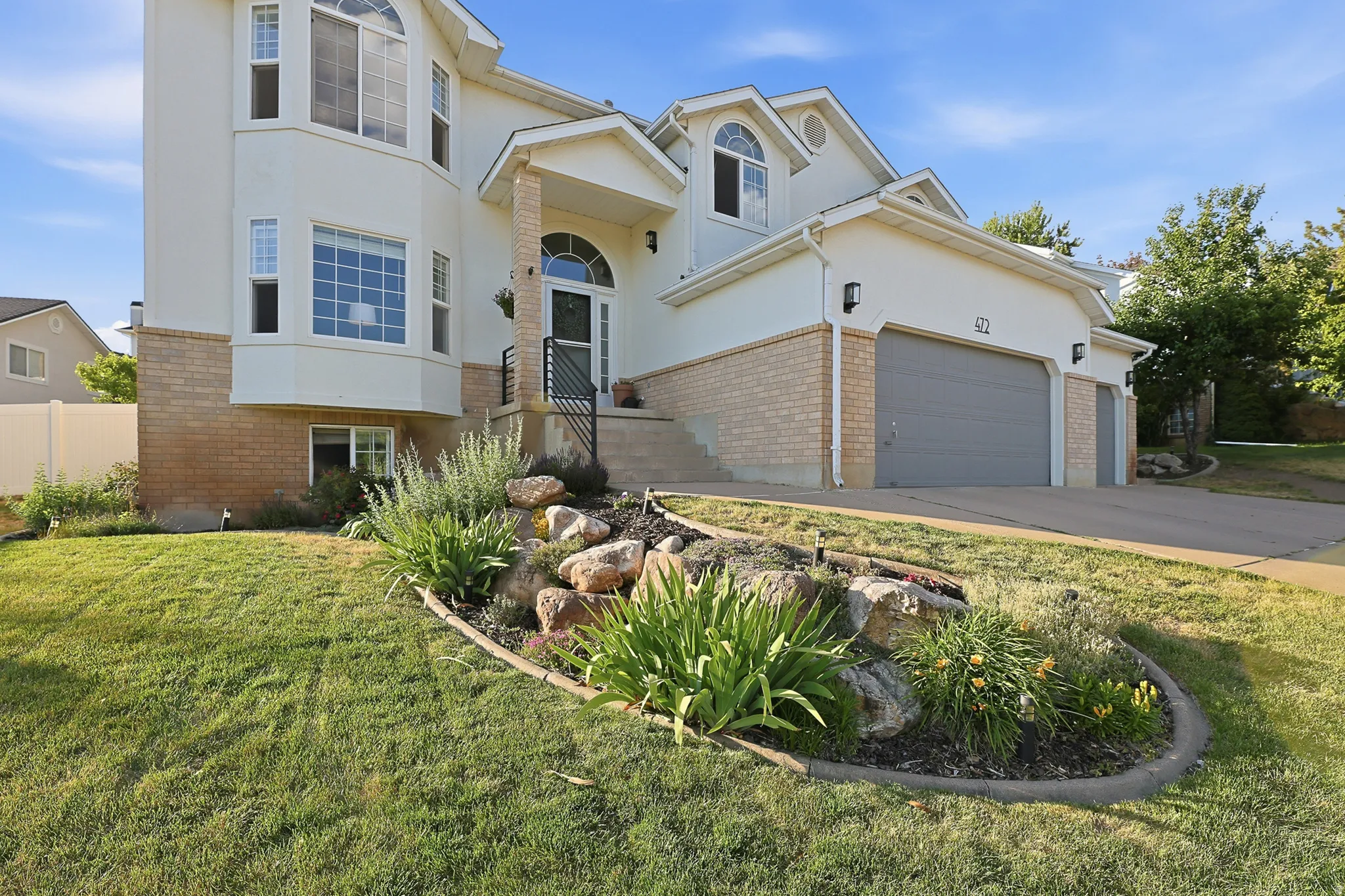 Light-toned stucco exterior with a brick foundation accent