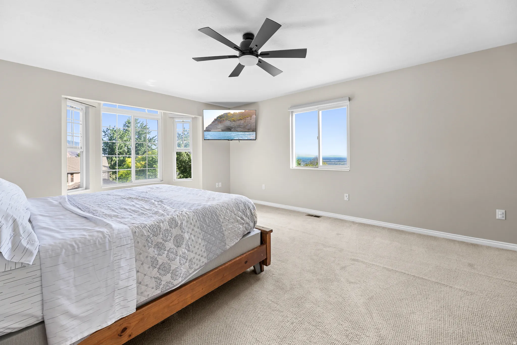 Spacious room featuring multiple windows, neutral tone walls, and light-colored carpeting