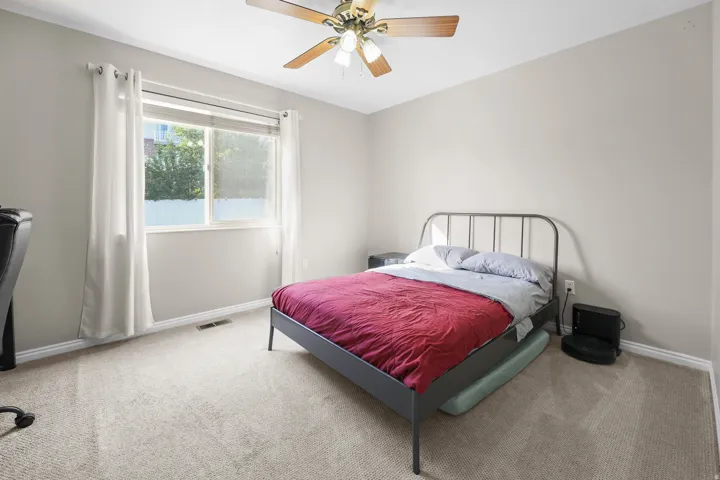 Carpeted room featuring a ceiling fan with light fixture, neutral wall paint, and a double window
