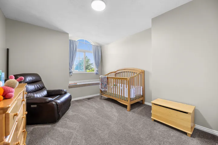 Bedroom featuring neutral wall colors, grey carpet, and a prominent arched window