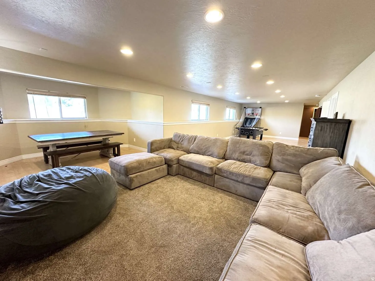 Spacious recreational room featuring recessed lighting, light-toned walls with chair rail molding, and carpeted flooring