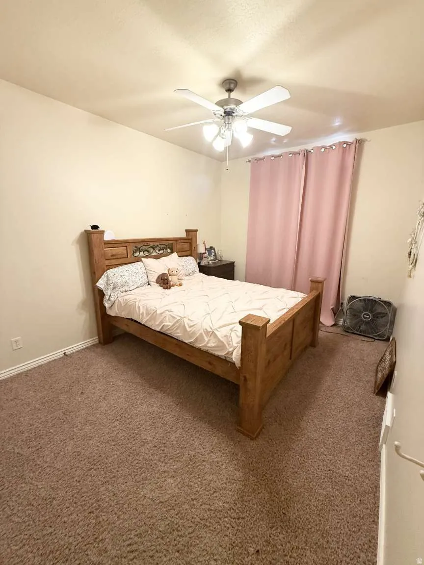 Carpeted bedroom featuring a ceiling fan with integrated lighting and baseboard trim