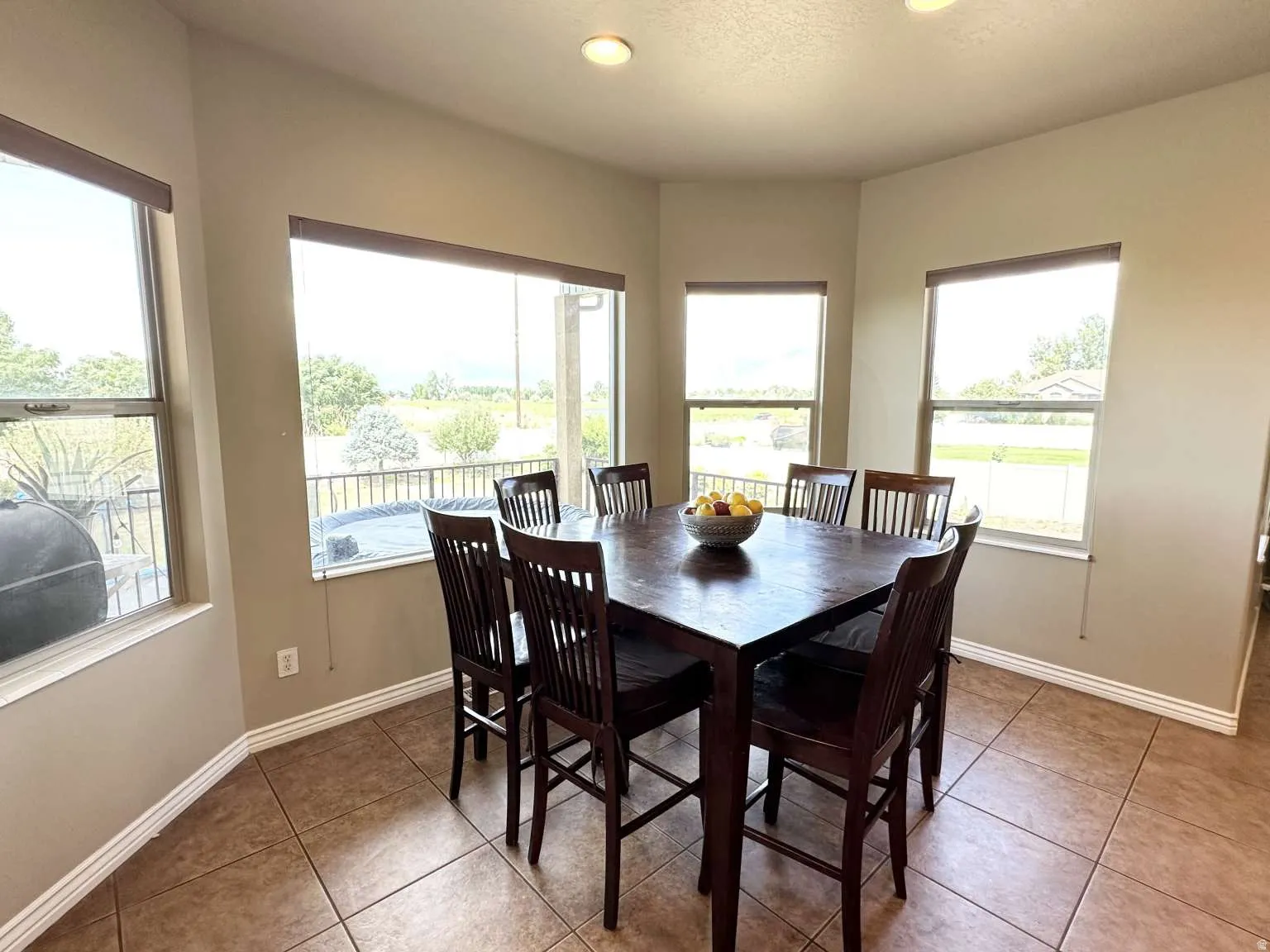 Bay window dining area featuring neutral wall tones, recessed lighting, tile flooring, and multiple windows