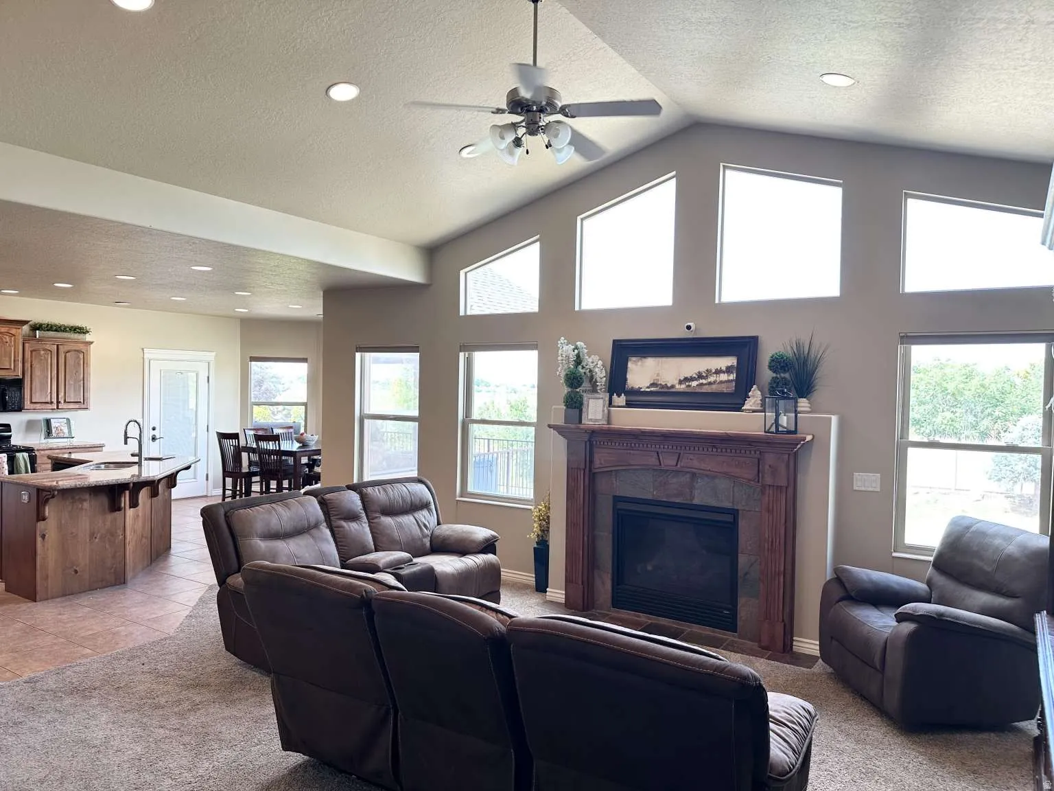 Vaulted ceiling living room featuring a fireplace with a wood-finish mantel and stone surround
