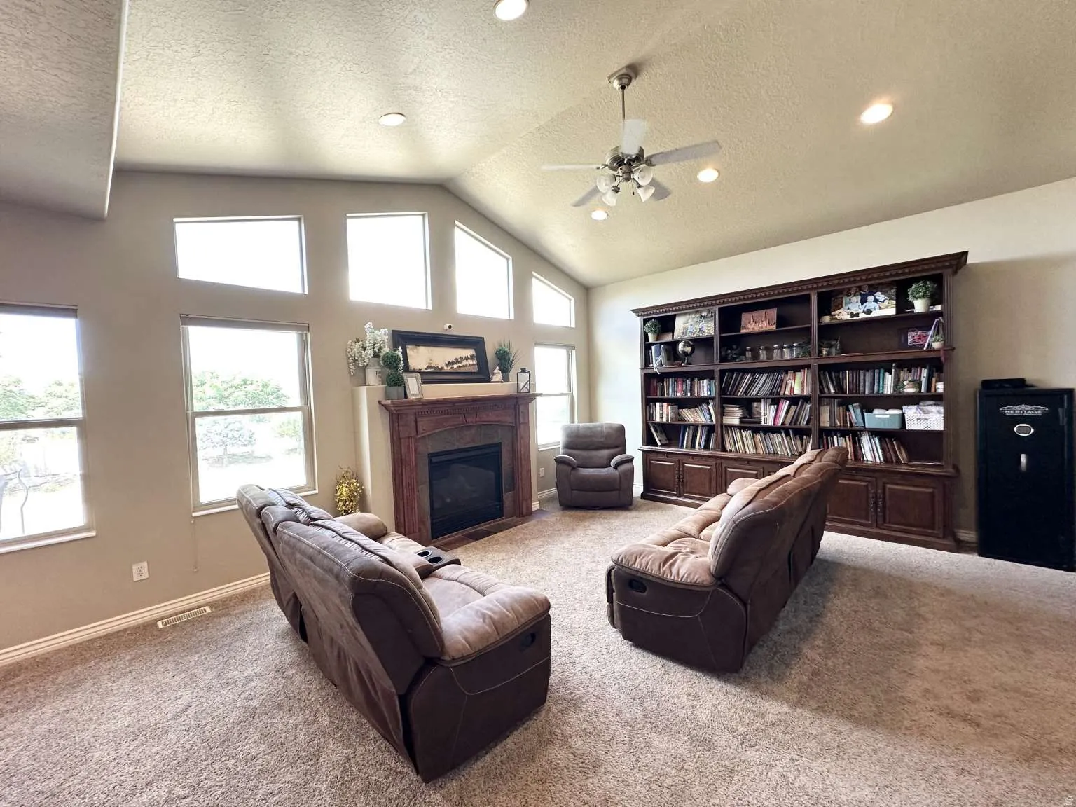 Spacious living area featuring a vaulted ceiling, recessed lighting, and a prominent built-in wood-finish bookcase