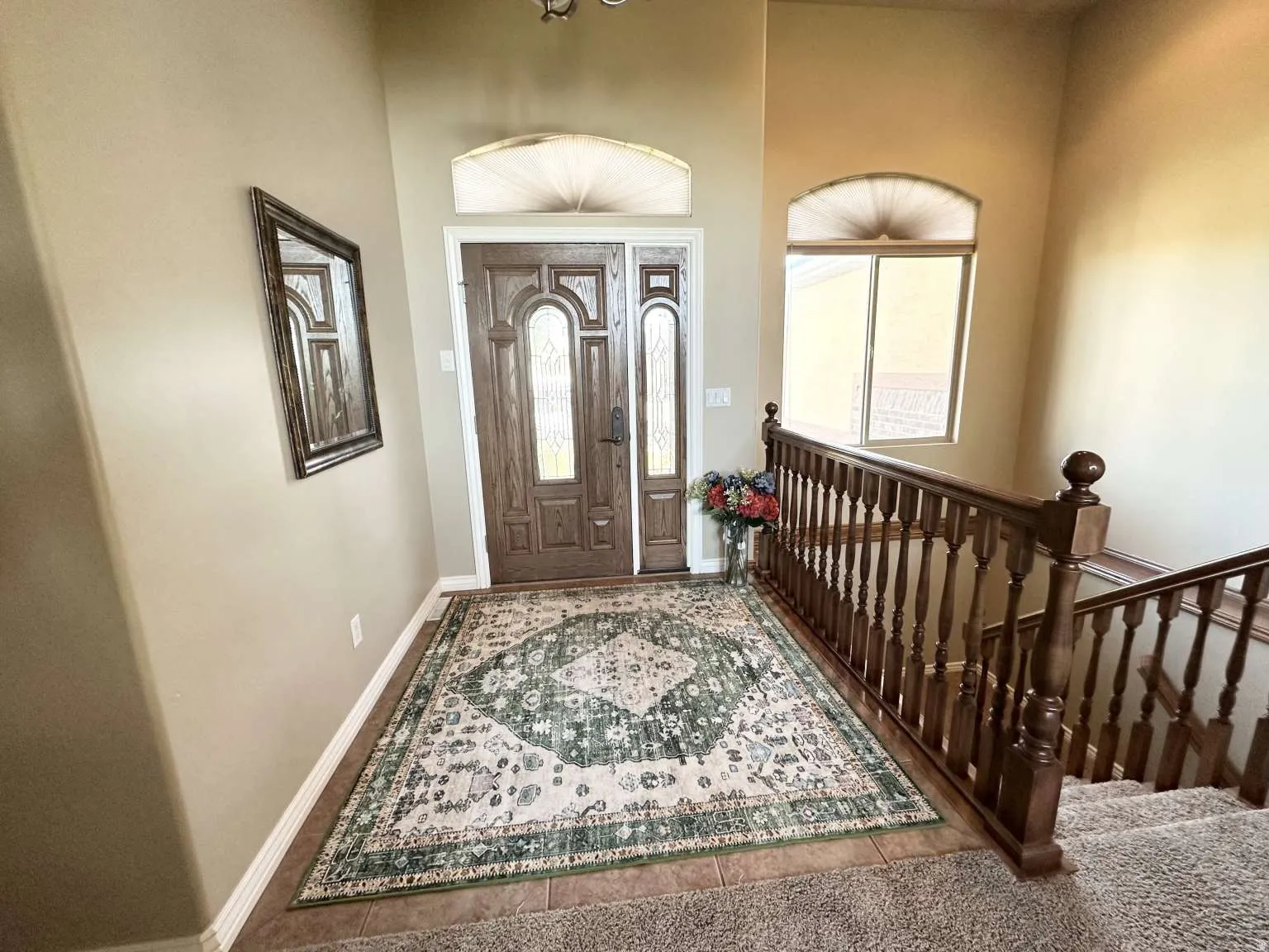 Entryway featuring a wood-panel door with decorative glass, tiled flooring, and an arched transom window