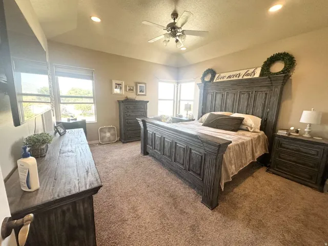 Carpeted bedroom with a vaulted ceiling and recessed lighting