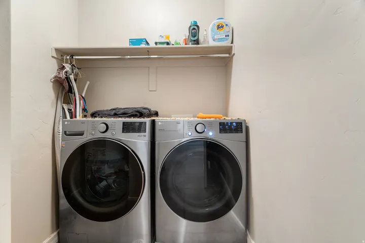 Dedicated laundry area featuring a built-in shelving unit, overhead hanging rod, and textured light-toned walls
