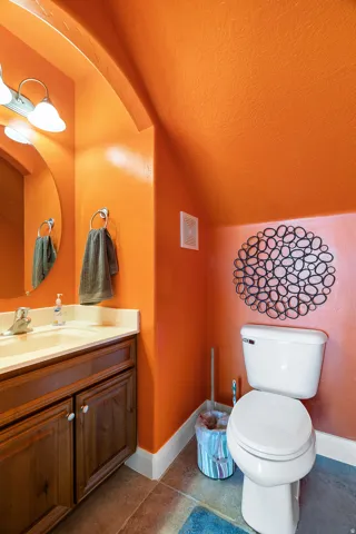 Powder room with a wood vanity, light-toned countertop, and an oval mirror