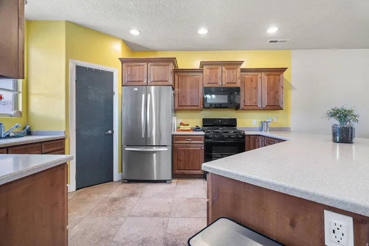 Kitchen featuring warm-toned cabinetry, light-toned countertops, and stainless steel appliances