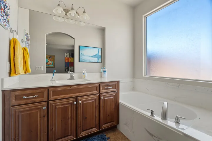 White soaking tub with brushed nickel fixtures, complemented by a large privacy window