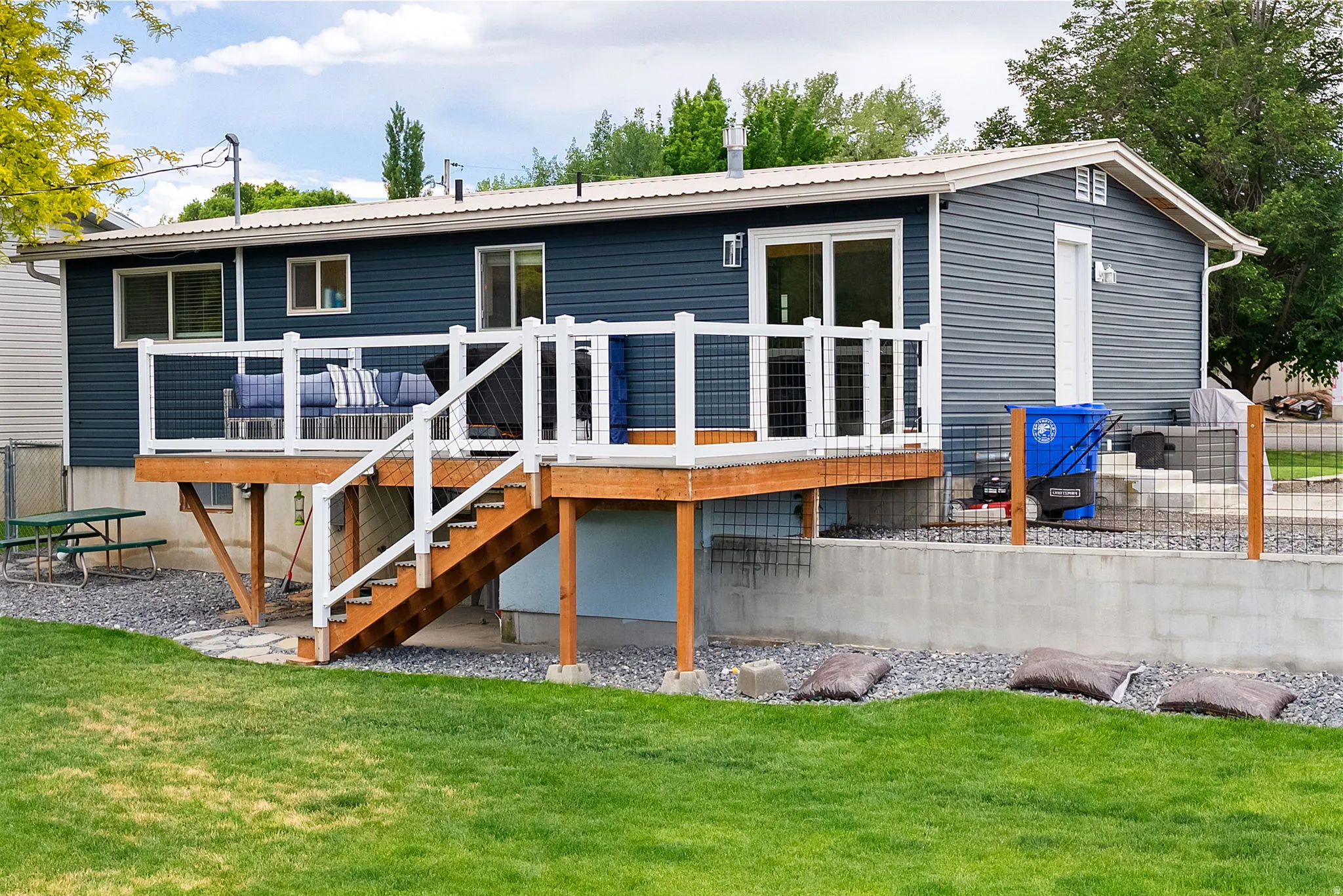 Rear exterior featuring a spacious wooden deck with white railing and stairs to the yard