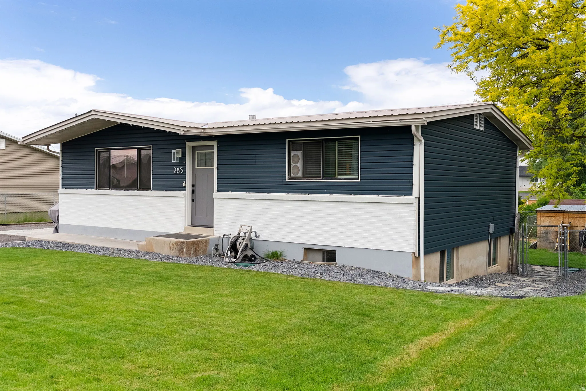 Split-level residence featuring a dark blue siding upper exterior and a white brick lower exterior