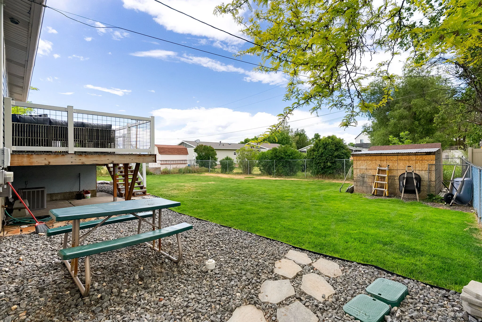 Expansive backyard featuring a large lawn area, a gravel patio, and a storage shed