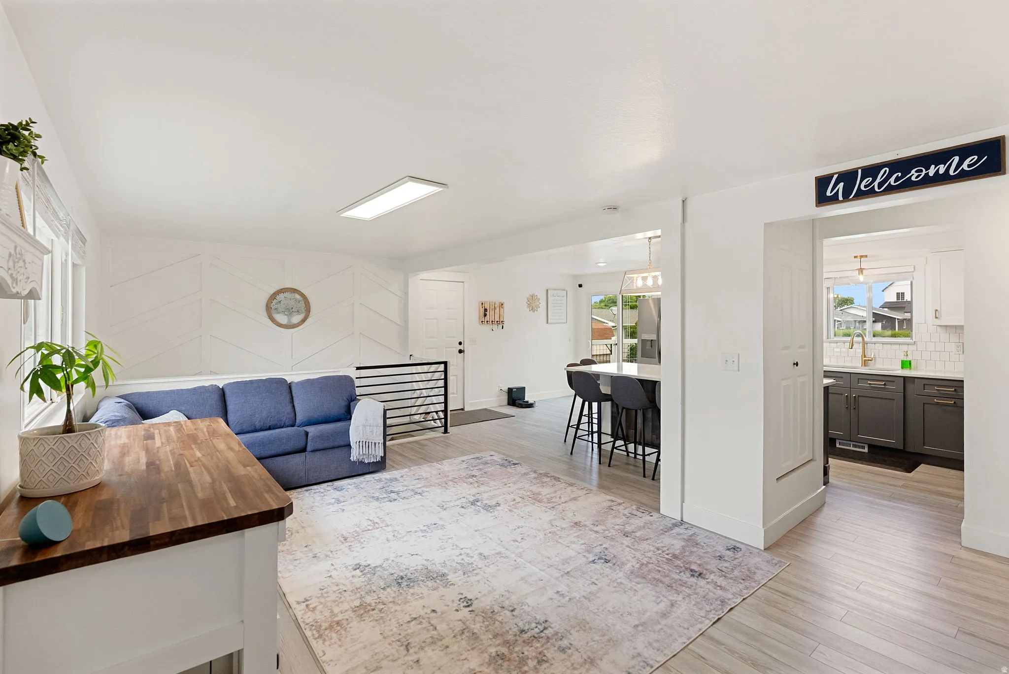 Open-concept living space featuring wood-finish flooring and a geometric accent wall