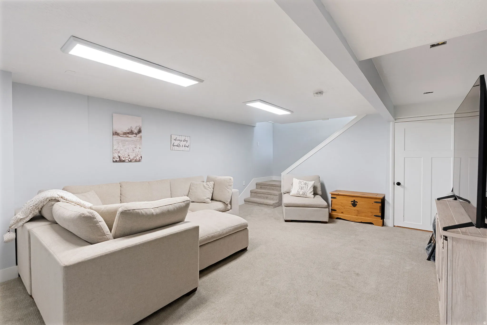 Carpeted lower-level room featuring light gray walls, white trim, and recessed lighting