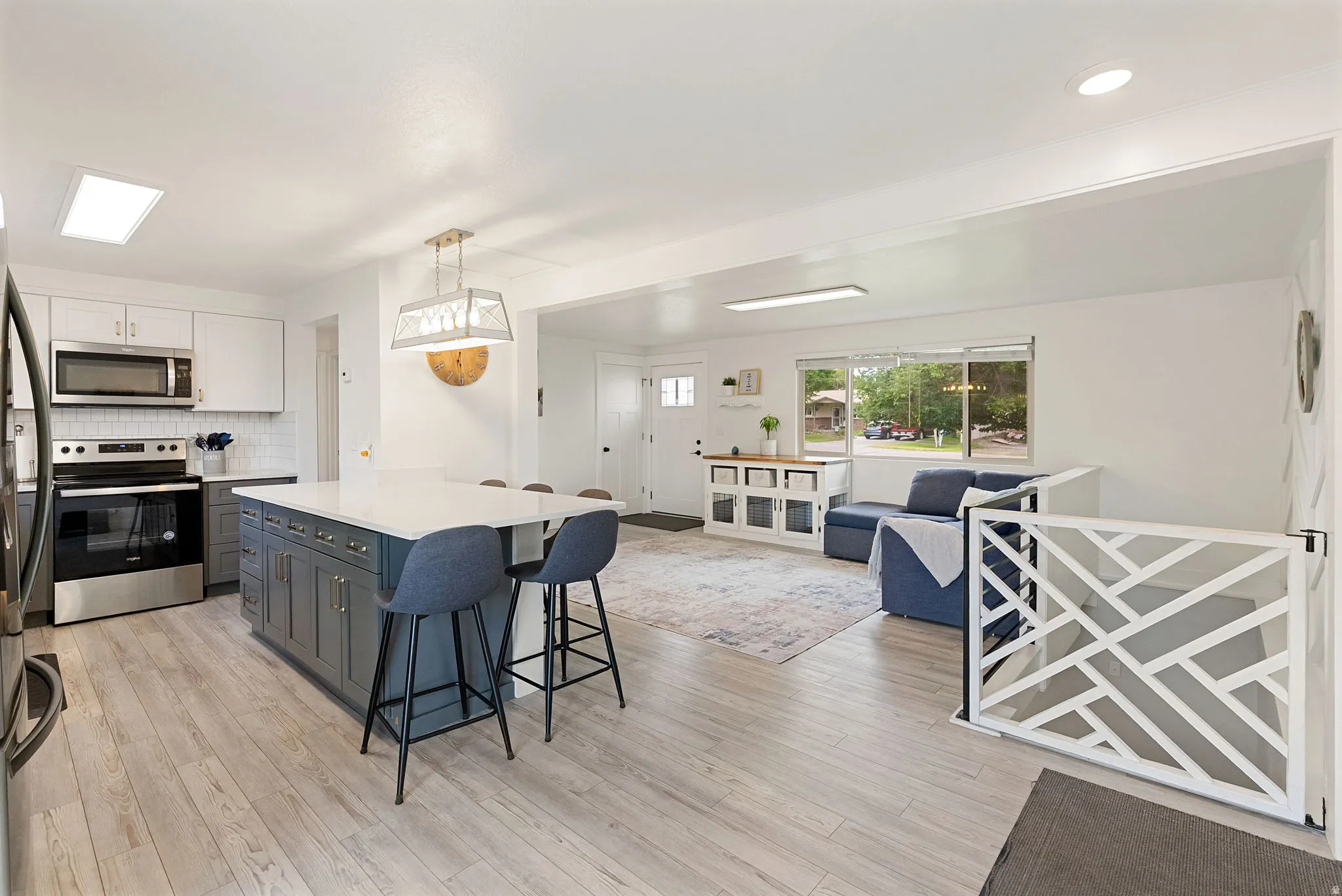 Bright kitchen featuring a substantial island with seating, a skylight, and stainless steel appliances