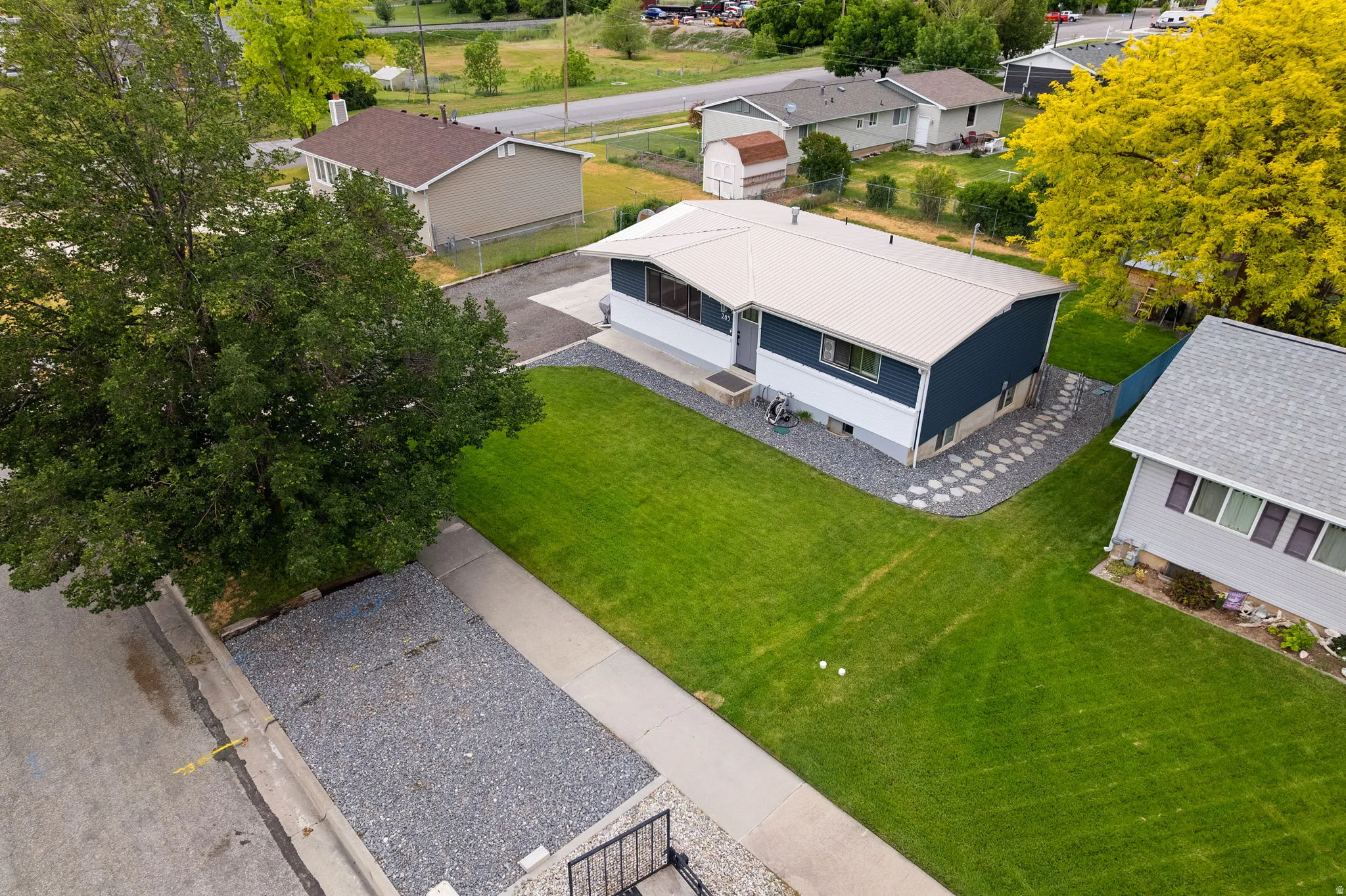 Single-story residence featuring a metal roof, dark blue and white siding, and a manicured lawn
