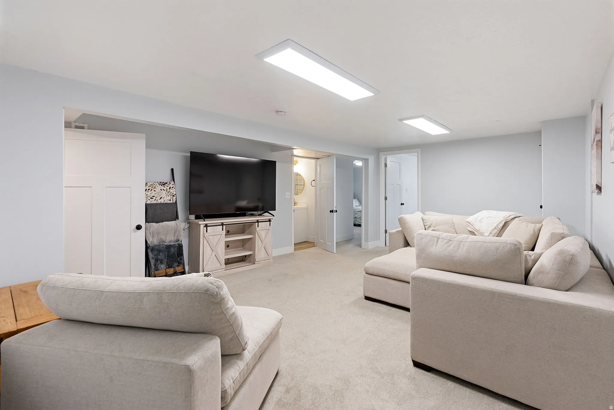 Expansive lower level featuring light gray walls, recessed rectangular ceiling lighting, and soft carpeting