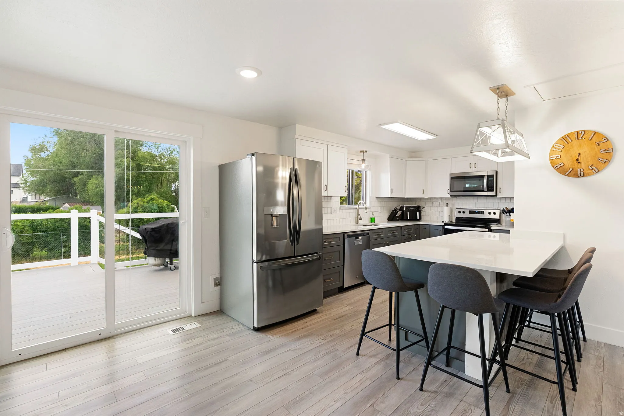 Open-concept kitchen with wood-finish flooring, white upper cabinetry, and gray lower cabinetry