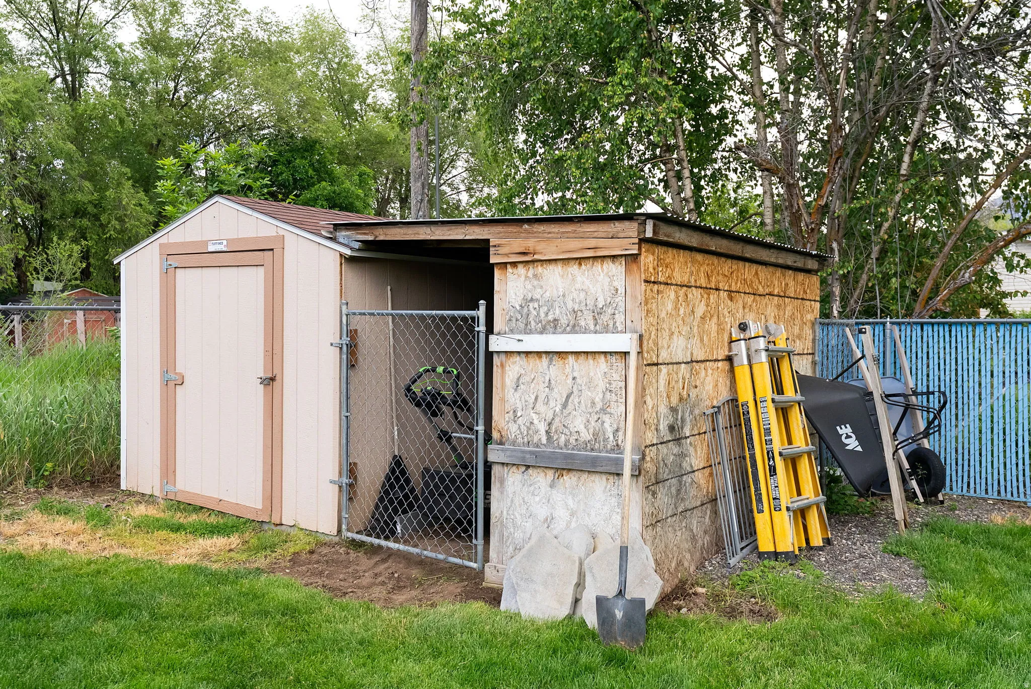 Two-part outdoor storage structure featuring a gabled roof shed with a single entry door and an attached open-sided lean-to