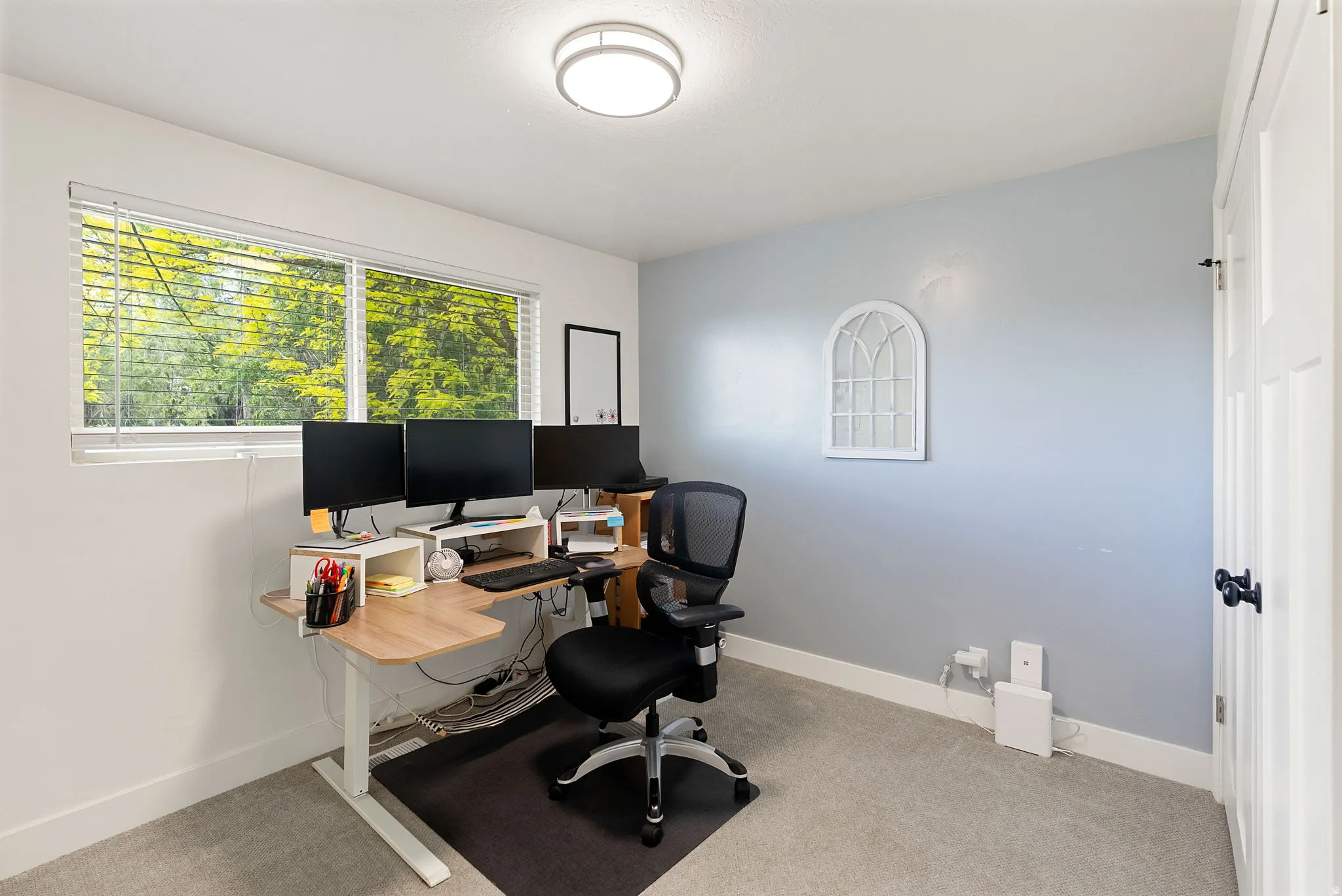 Room featuring a window with horizontal blinds, light-colored walls, and gray carpeting