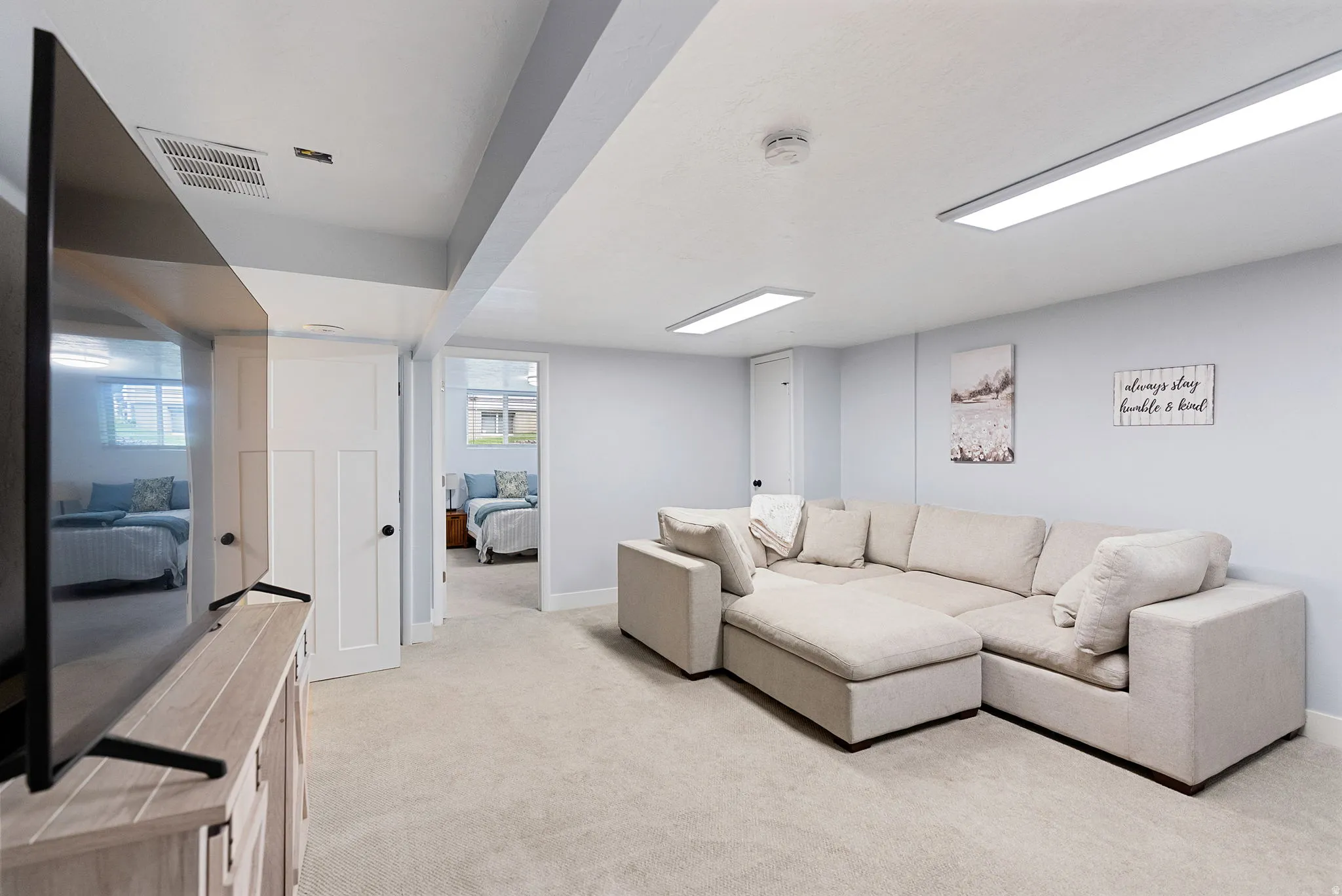 Carpeted recreation room featuring overhead panel lighting and a neutral color palette