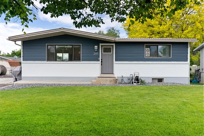 Property exterior featuring blue horizontal siding, white lower facade, and a gray front door with integrated window