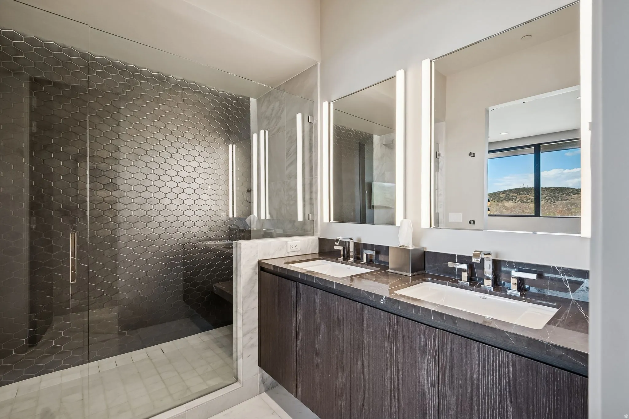 Full bath with double vanity and a shower stall