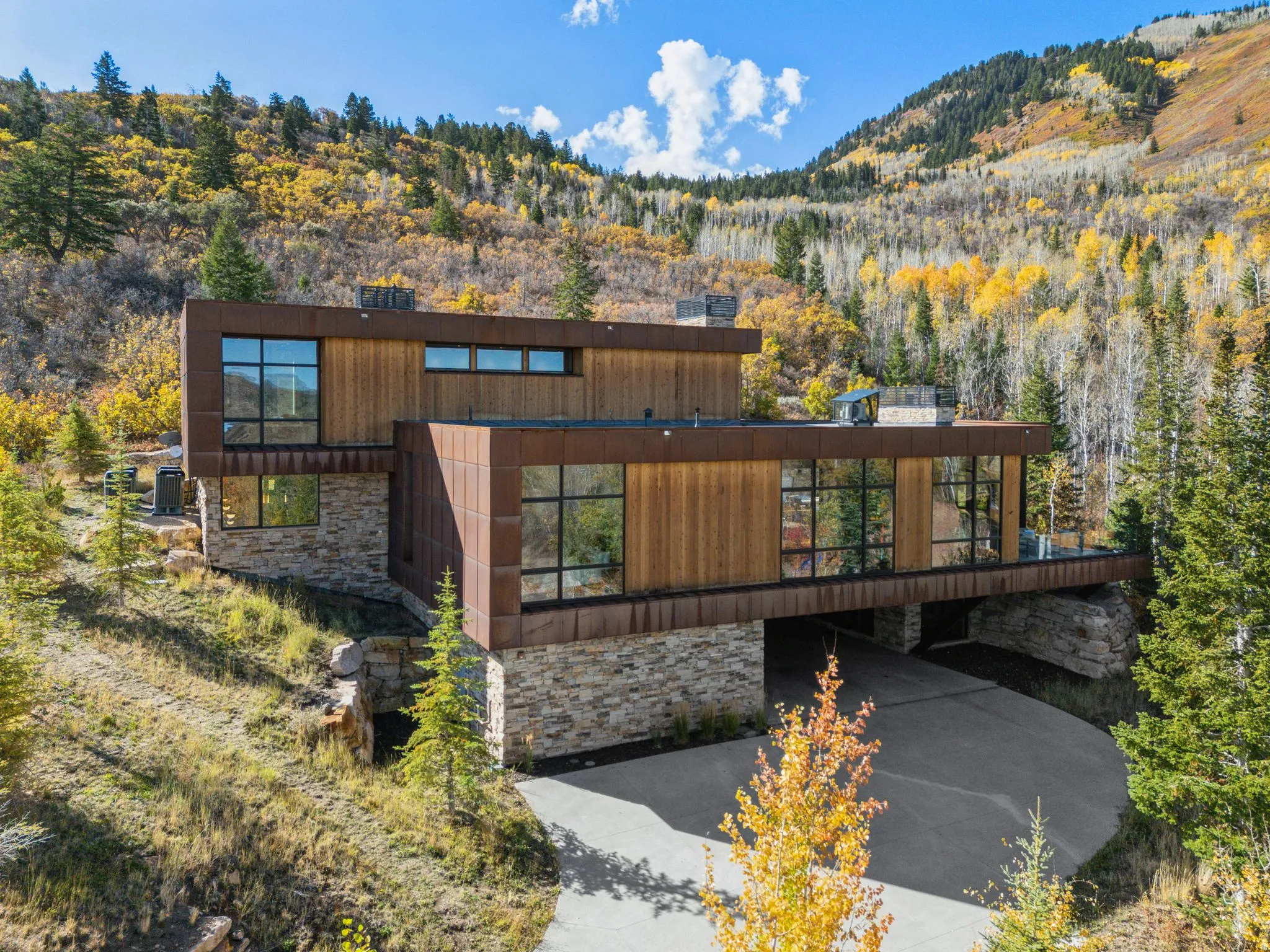 View of front facade featuring stone siding, a mountain view, a view of trees, and a carport