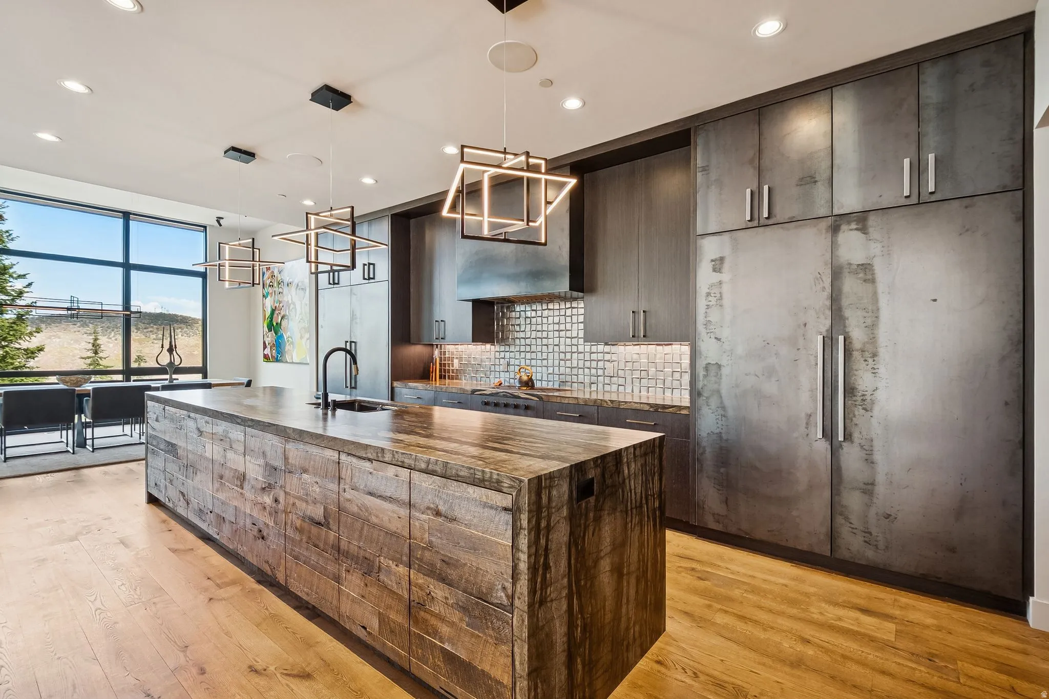 Kitchen with an island with sink, tasteful backsplash, light wood-type flooring, and dark wood finish cabinetry