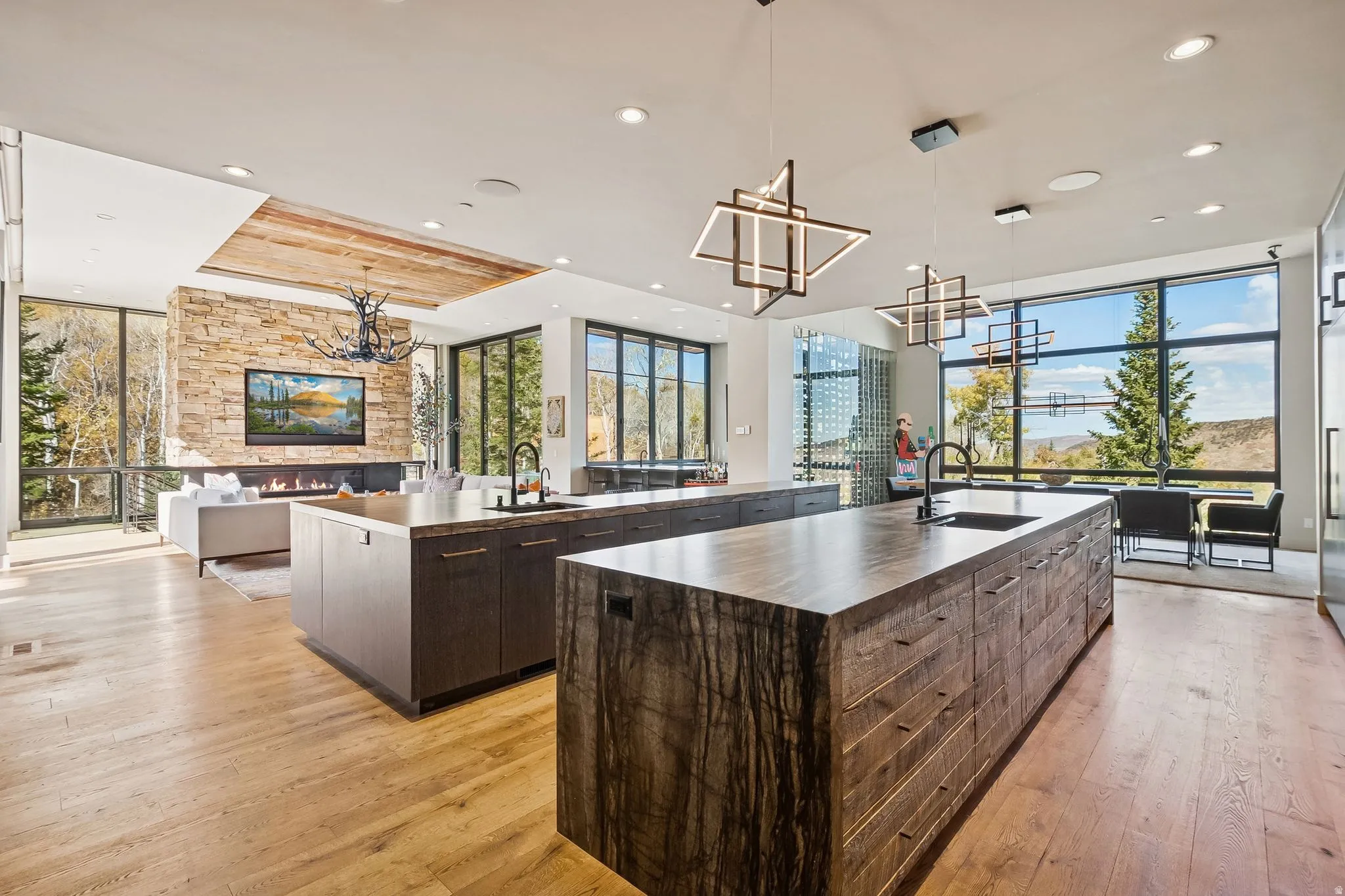 Kitchen featuring hanging lights, expansive windows, open floor plan, dark wood finish cabinetry, and plenty of natural light