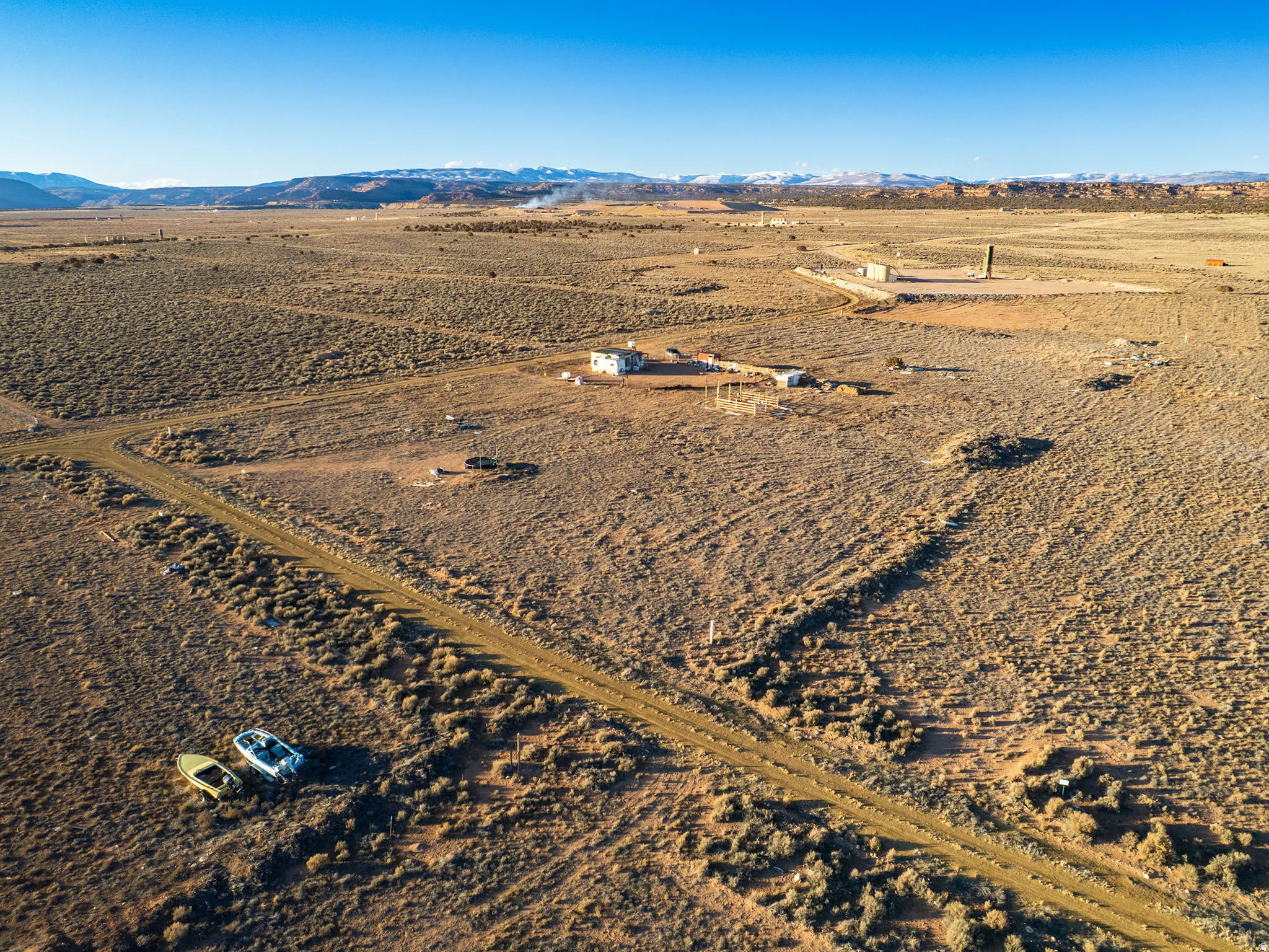 Expansive desert landscape featuring a dirt road and distant snow-capped mountains