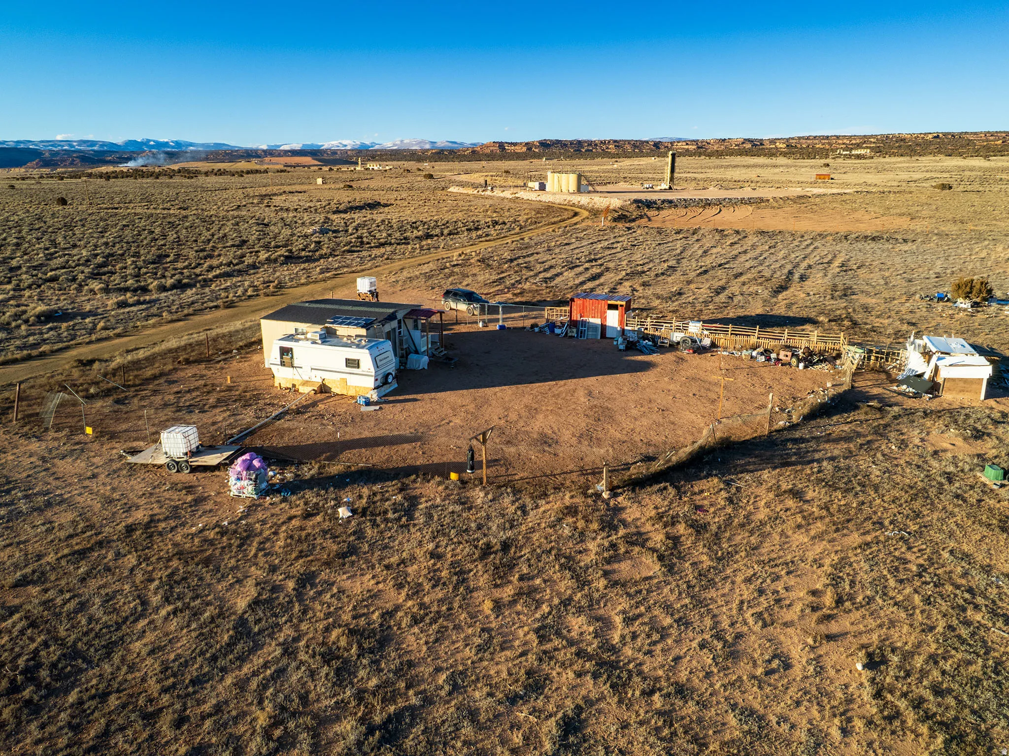 Expansive rural property featuring a red outbuilding, perimeter fencing, and a gravel driveway