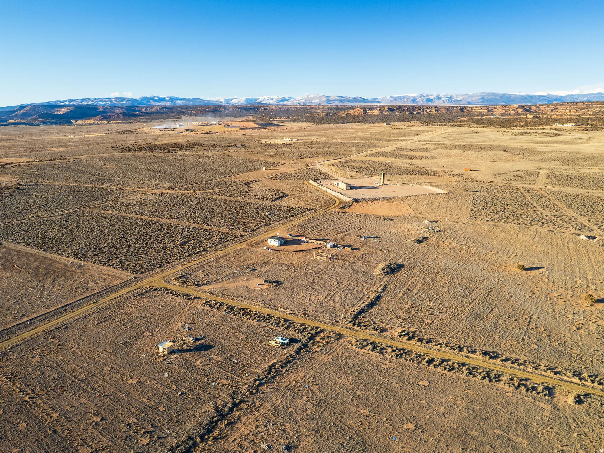 Expansive arid landscape featuring a distant mountain range with snow-capped peaks