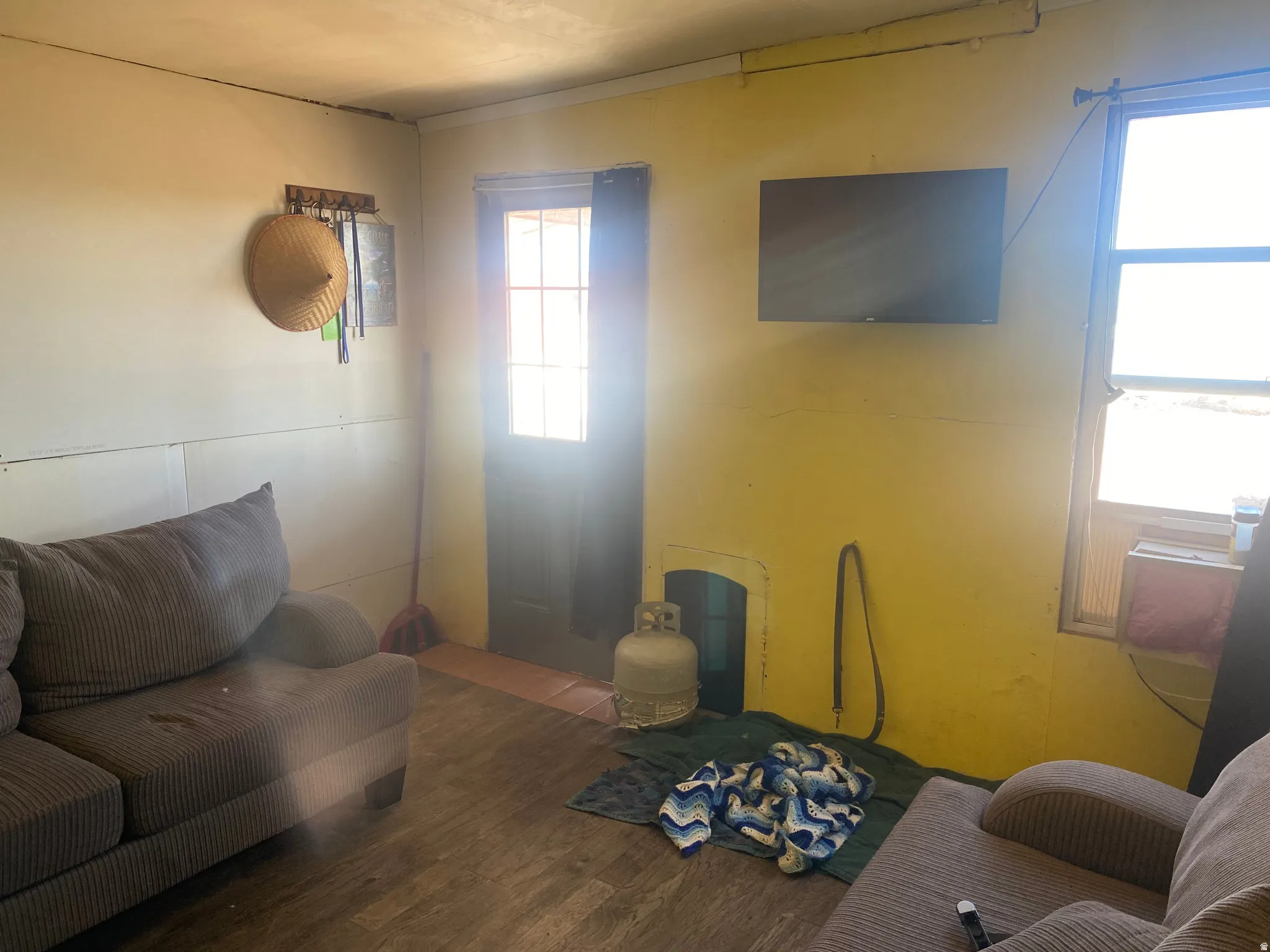 Interior space featuring wood-finish flooring, a wall-mounted display, and a window unit