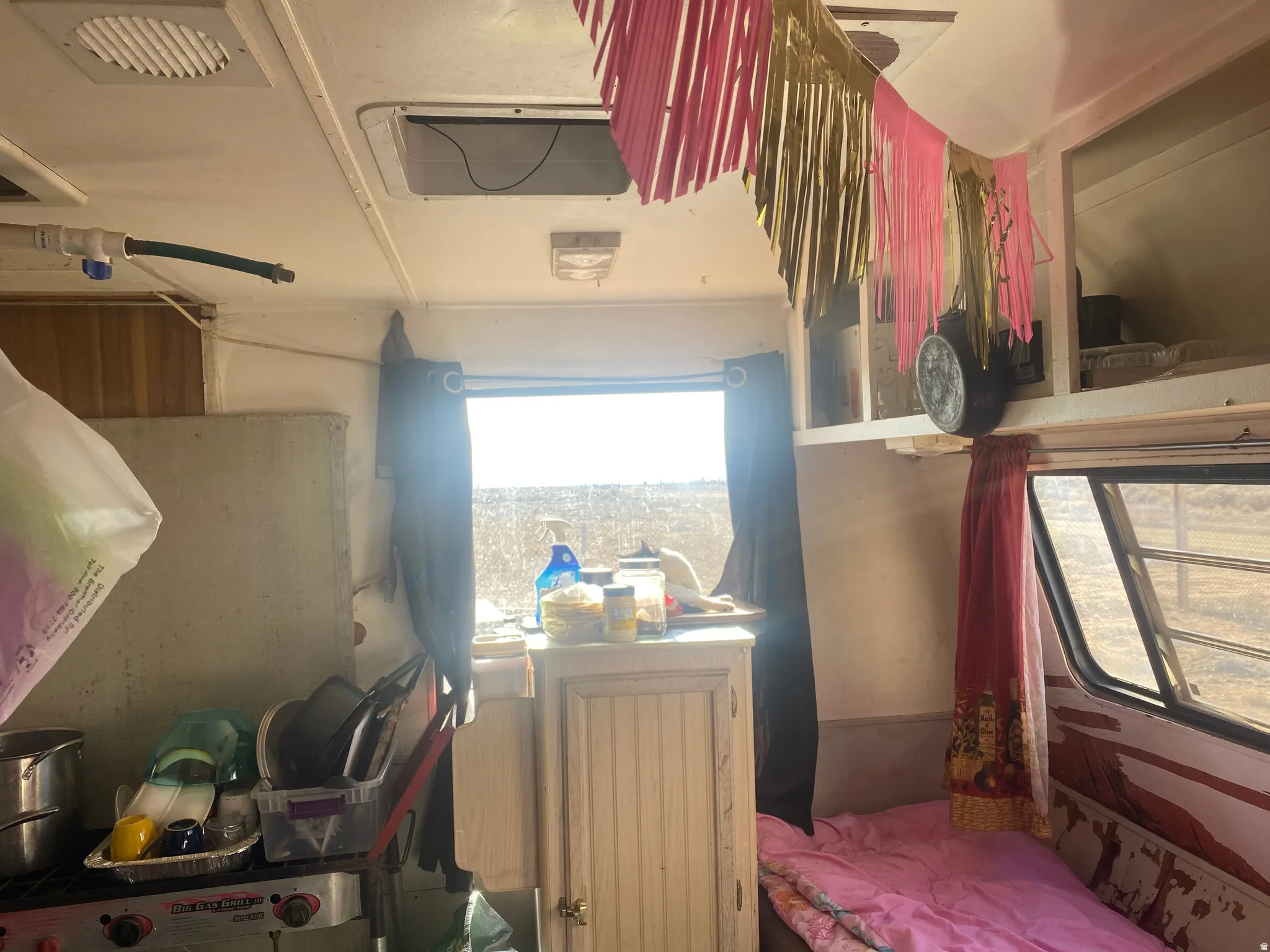 Compact interior with a window offering natural light, overhead cabinetry, and a built-in sleeping area