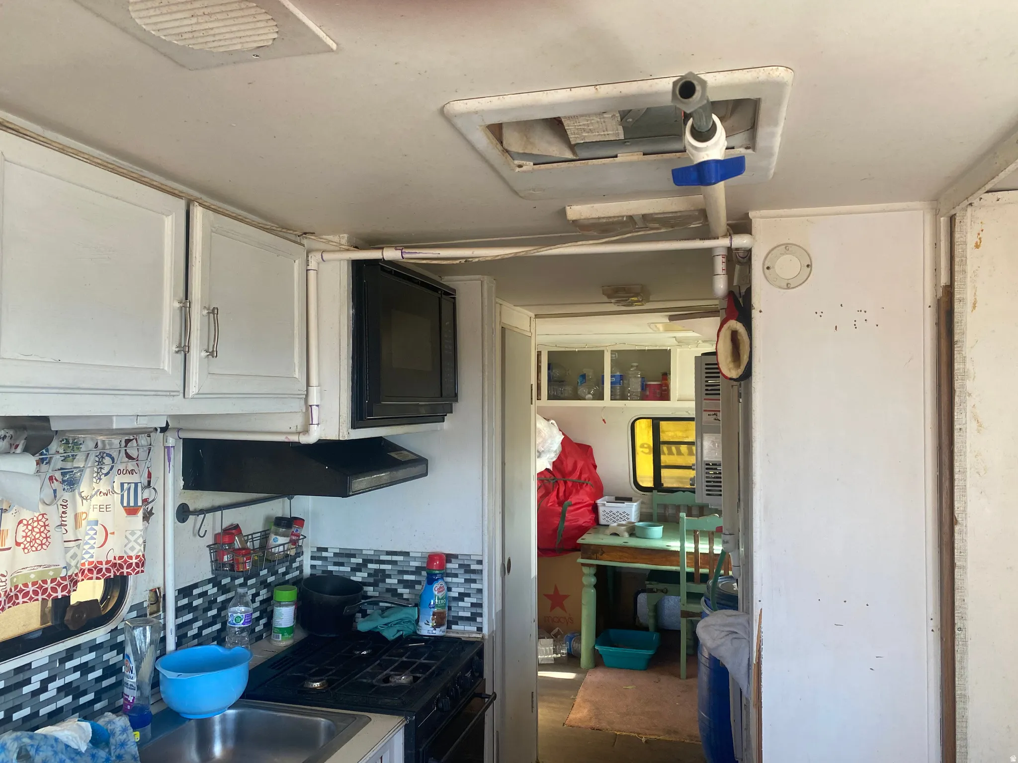 Compact kitchen area featuring a built-in microwave, range hood, and a gas cooktop