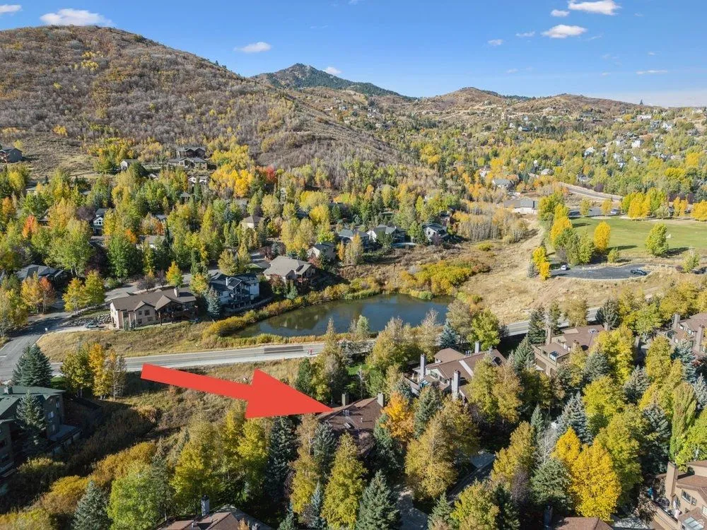 Mountainous landscape with a residential community, featuring a pond and varied autumn foliage