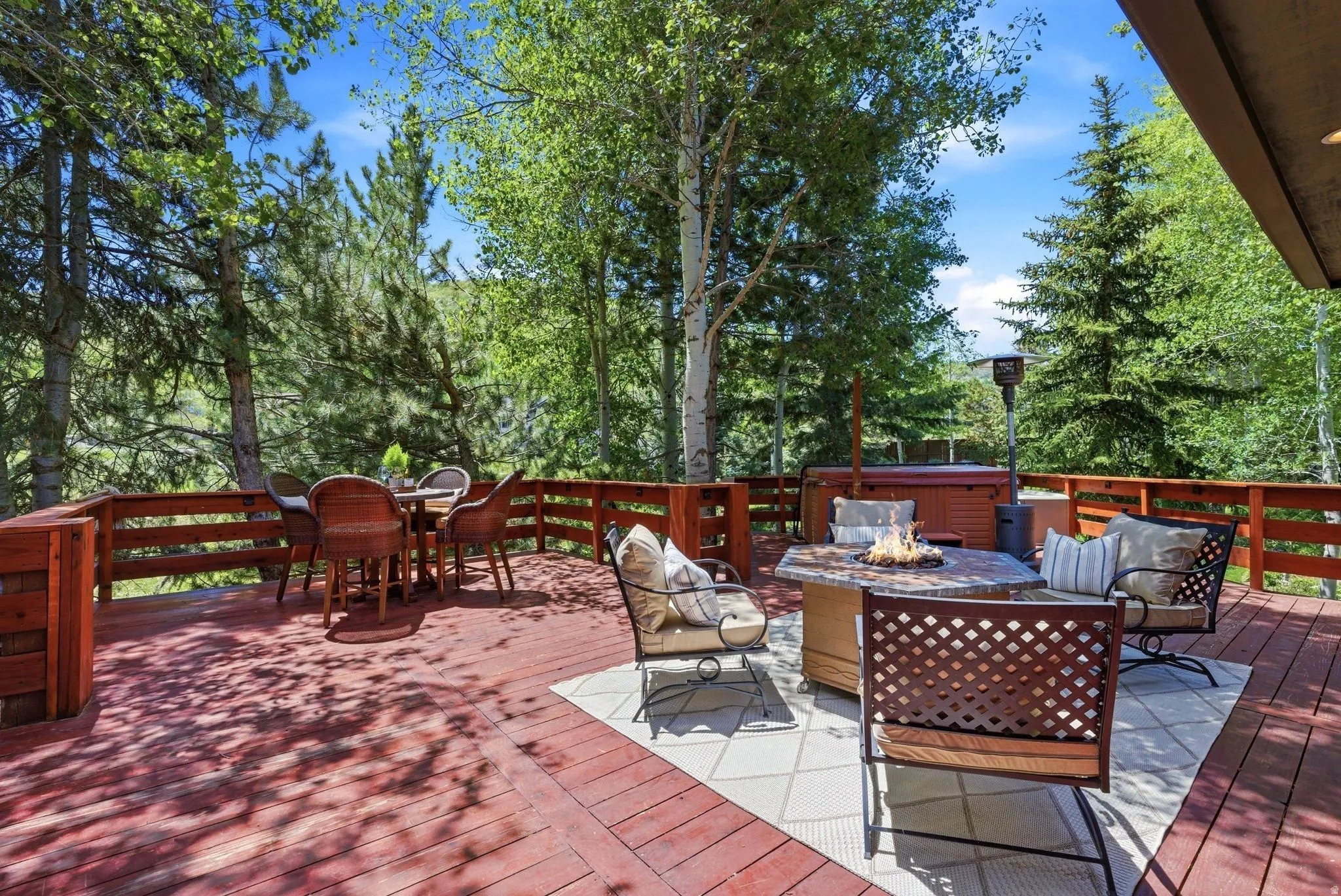Spacious wooden deck featuring a built-in hot tub and perimeter railing