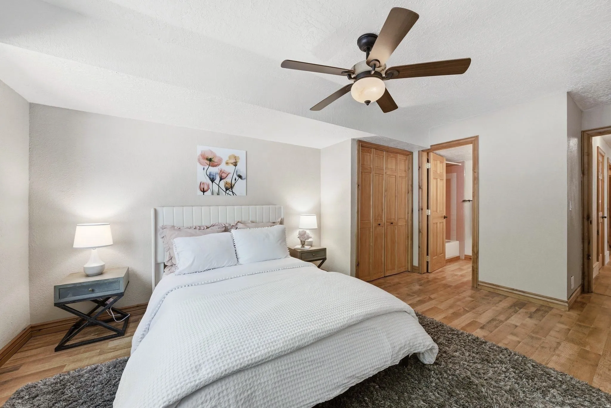 Bedroom featuring wood-finish flooring, a ceiling fan with integrated lighting, and light-toned walls