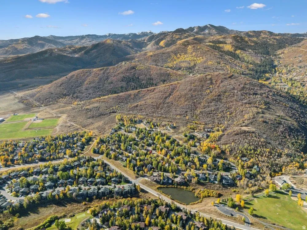 Expansive aerial landscape highlighting a developed residential area with numerous homes amidst varied autumn foliage