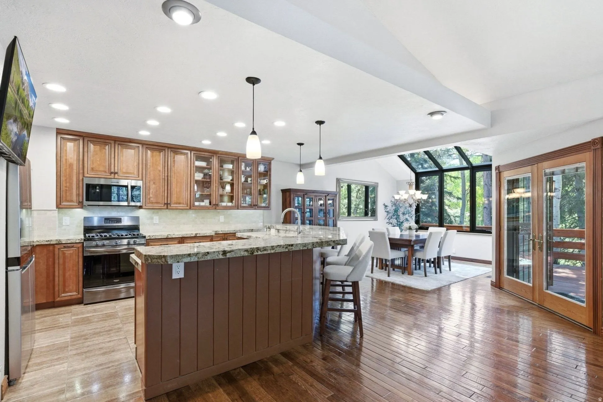 Kitchen and dining area featuring wood-finish flooring, recessed lighting, and an island with pendant lights
