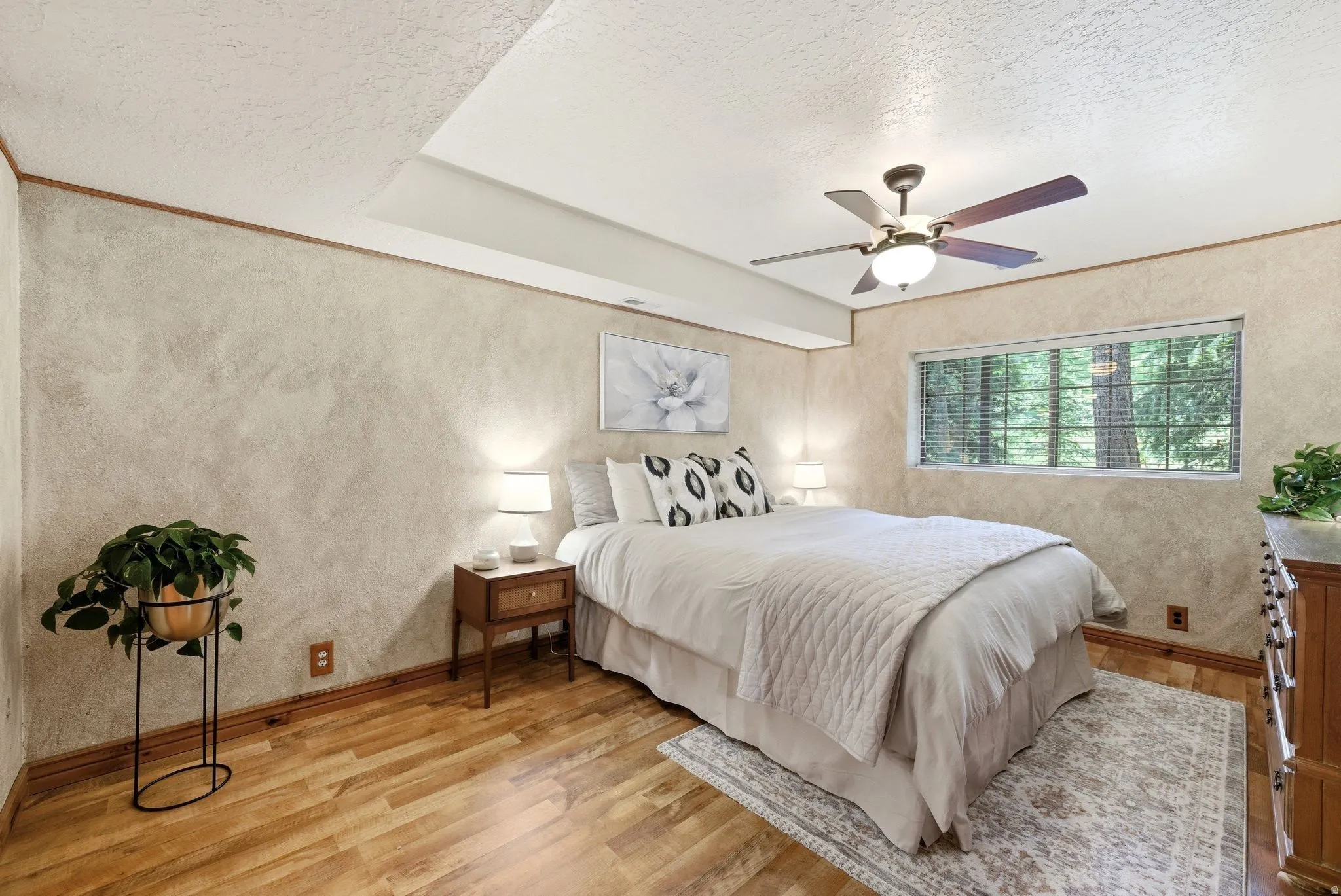 Bedroom featuring wood-finish flooring, textured walls, and a recessed ceiling element