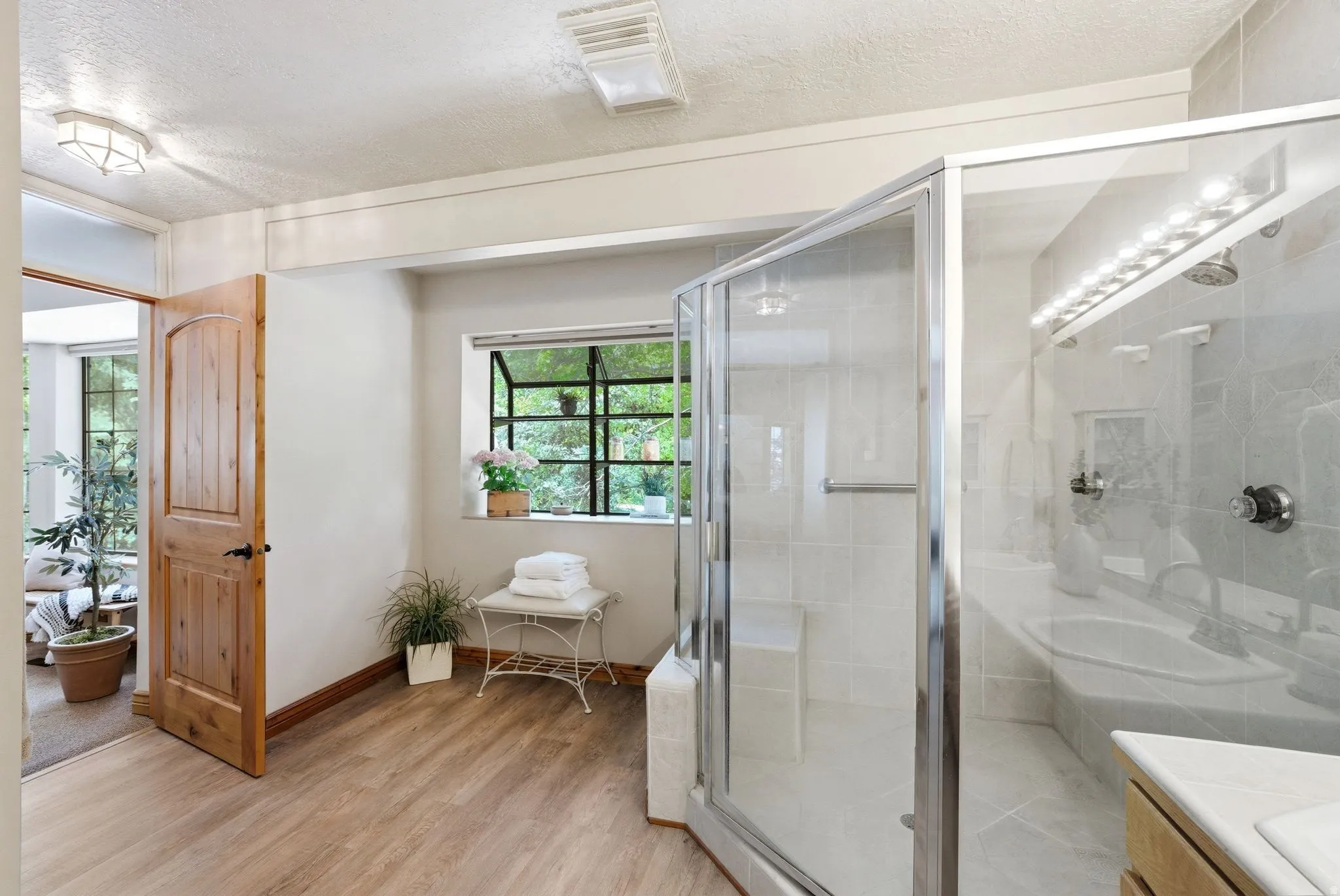 Spacious bathroom featuring wood-finish flooring and a walk-in shower with a built-in bench