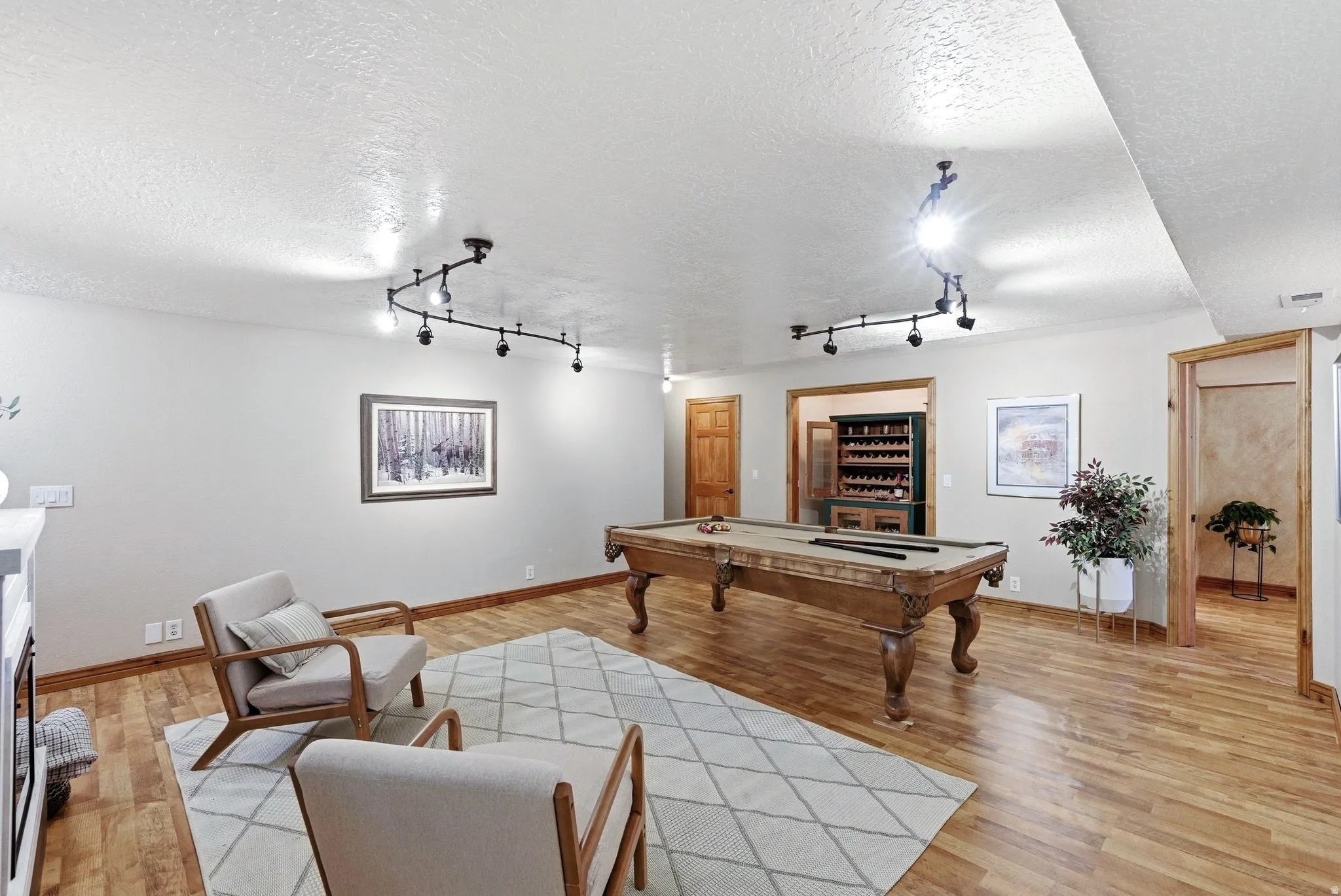 Spacious recreation area featuring wood-finish flooring, track lighting, and light-toned walls